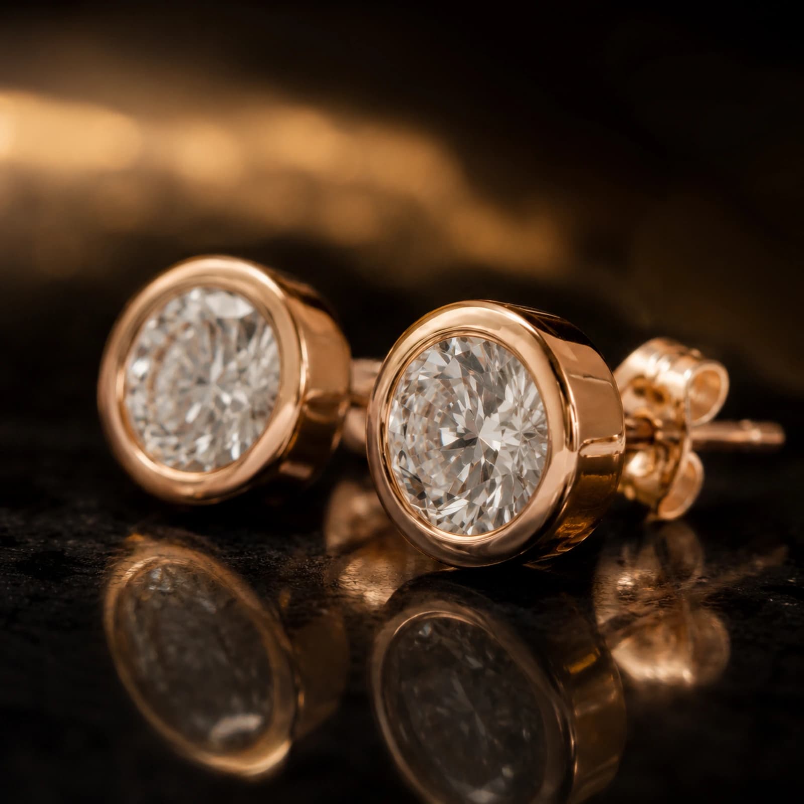 Kolczyki bezel studs z diamentami laboratoryjnymi w różowym złocie w ujęciu pod kątem na ciemnym tle