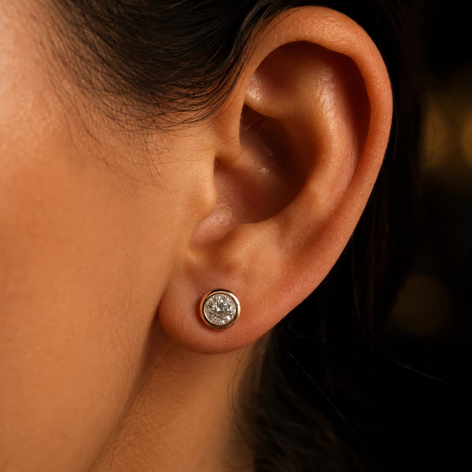 Kolczyki bezel studs z diamentami laboratoryjnymi w różowym złocie noszone przy uchu