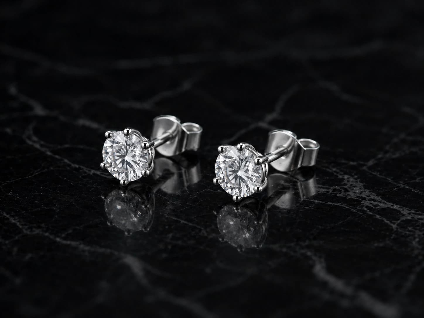 Kolczyki solitaire z diamentami w białym złocie, oprawa 4 pazurki — ujęcie pod kątem 3/4